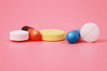 Variety of medicine capsules and pills on pink background.