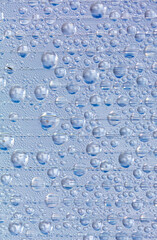Water drops on blue glass as an abstract background.