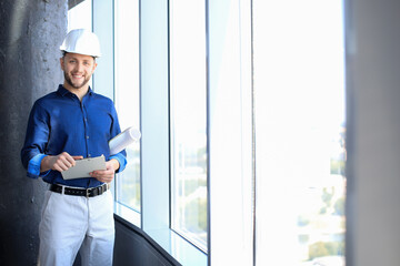 Shot of smiling male architect wearing hardhat and inspecting new building.