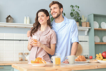 Beautiful couple hugging each other and looking away in kitchen in the morning.