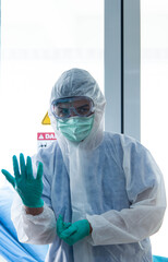 Doctors in protective suit wear medical rubber gloves looking at camera in front of CORONA VISRUS or COVID-19 quarantine room at the hospital.