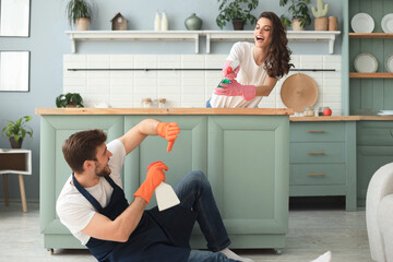 Young happy couple is having fun while doing cleaning at home.
