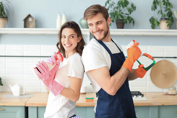 Young happy couple is having fun while doing cleaning at home.