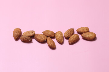 nuts almonds scattered on a pink background.