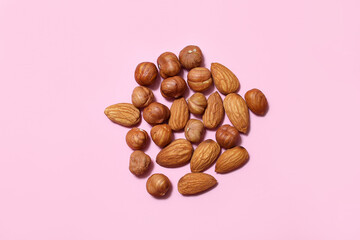 nuts almonds and hazelnuts scattered on a pink background. Natural vitamins. Healthy food.
