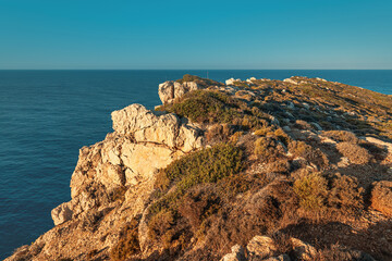 Fototapeta na wymiar View of small rocky cliff at the blue sea