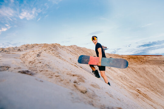 Snowboarder man sand boarding on dunes in Dubai, UAE