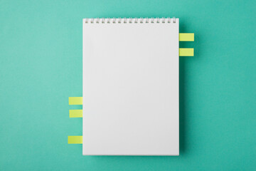 Above flat lay overhead close up view photo image of clear textbook with spiral and memo stickers with copy space isolated teal turquoise desk backdrop