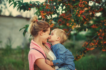 Portrait of a boy in the arms of his mother on a walk . Family values .