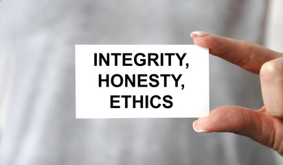 The girl holds a card with integrity, HONESTY, ETHICS, a grey T-shirt.