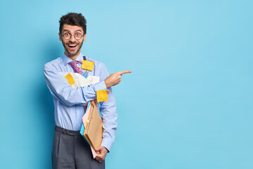Cheerful businessman holds papers with diagrams and formulas dressed in formal clothes indicates...