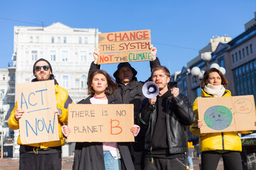 A group of people with banners and a megaphone in hand are protesting in the city square for svae planet clean world act now