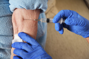 A 90-year-old woman is given the covid-19 vaccine by a doctor. Vaccination of the elderly. Senior...