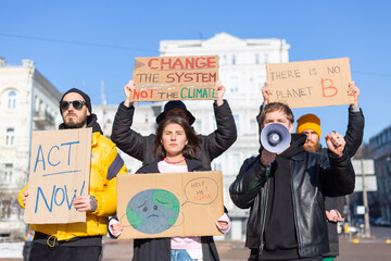 A group of people with banners and a megaphone in hand are protesting in the city square for svae...