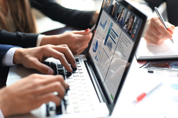 Business professionals working together at office desk, analyzing financial statistics displayed on the laptop screen. Webcam group conference with coworkers on laptop.