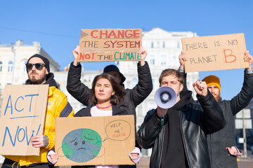 A group of people with banners and a megaphone in hand are protesting in the city square for svae...