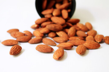 Almonds pour from cup on white background. concept of vegan raw ingredient for vegetarian snack and healthy food (select focus)
