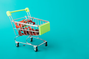 Valentine's Day love gifts, lots of hearts in a shopping cart trolley from the supermarket on a green background with copy space