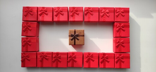 Frame, rectangle from red gift boxes with one brown box in the middle. Top view perspective.