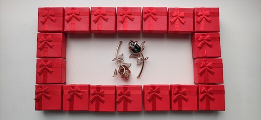 Frame, rectangle from red gift boxes with brooch decoration in the middle. Top view perspective.