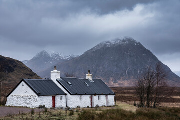 Stunning majestic landscape image of Buachaille Etive Mor and River Etive in Scottish Highlands on a Winter morning with moody sky and lighting