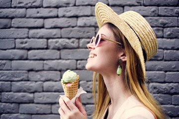 Pretty woman in elegant style hat outdoors ice cream brick wall on background