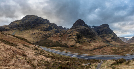 Majestic moody landscape image of Three Sisters in Glencoe in Scottish Highlands on a wet Winter day wit high water running down mountains
