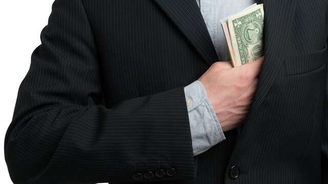 Man hide bribe money in his inner pocket of a jacket closeup. Hand shove stack of money in pocket.
