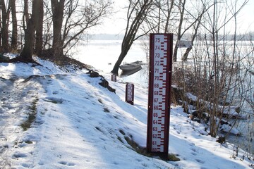 A water gauge on the Vistula River in Kepa Polska in Poland in winter. The name of the town and the...