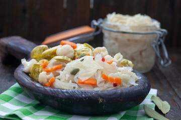 Homemade vegetables and sauerkraut pickling in rustic wooden plate. Healthy probiotic food full of vitamins.