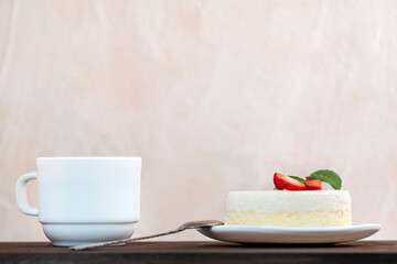Slice of cake and cup of coffee, side view. Piece of cheesecake garnished with strawberries.