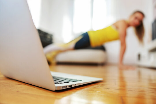Fitness instructor doing pushups at home and having online class with her students. - Powered by Adobe