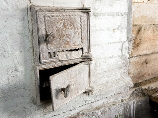 Two old iron doors of the firebox and ash-pan in a Russian stove, whitewashed with lime, in a country house.