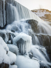 A frozen waterfall with ice  in winter. Winter background. Vertical photo.
