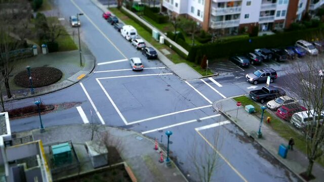 Top shot of four way traffic flow and pedestrians crossing the street with miniature effect
