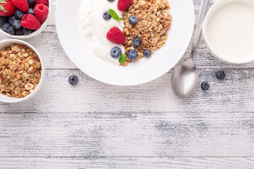 Homemade granola with yogurt and fresh berries in white ceramic plate on wooden background - Image