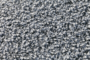 Beautiful crystals of snowy rime on ice surface of frozen Lake Baikal. Winter natural background. Cold texture with snowflakes on dark background (focus in the center of the frame). Top view, mock up