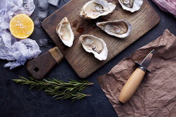 Fresh opened oysters, ice and lemon on a stone textured background.