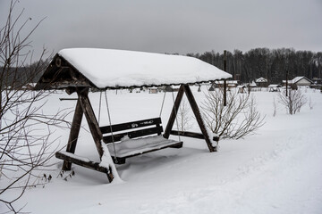 a bench with sun protection stands in a snow-covered field