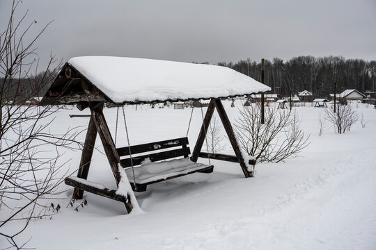 A Bench With Sun Protection Stands In A Snow-covered Field