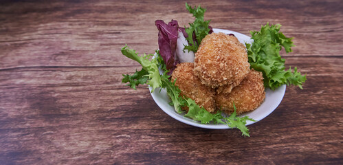 Croquetas caseras de jamón sobre plato blanco en una mesa de madera