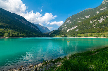 Fototapeta na wymiar Cavedine Lake. Panorama of the turquoise waters, with the alpine mountains in the distance rich in vegetation. Lake Cavedine is a small alpine lake in the Dolomites of Trentino, Trento, Italy.