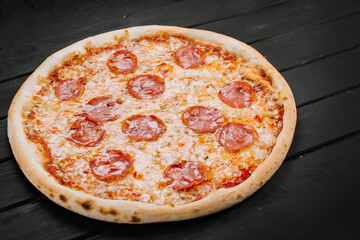 Delicious fresh pizza with meat and sausage on wooden background