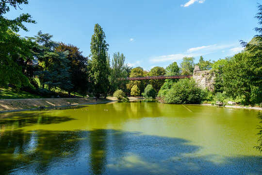 Lake in the Parc Buttes-Chaumont with footbridge in the background - Paris, France