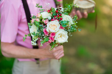 The bride's bouquet of fresh flowers in the hands of the groom