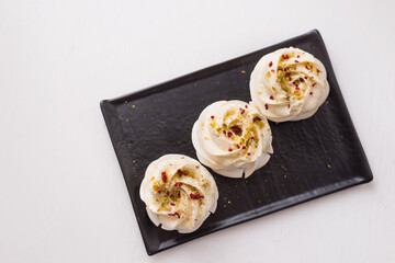 meringue cakes on a black plate. Pavlova dessert on a white background. The view from the top.