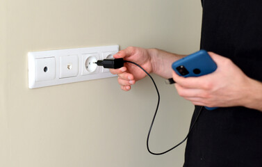 Hand inserting smarthone charger into a socket