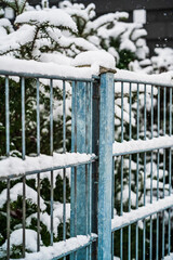 A vertical shot of a snow-covered metal fence