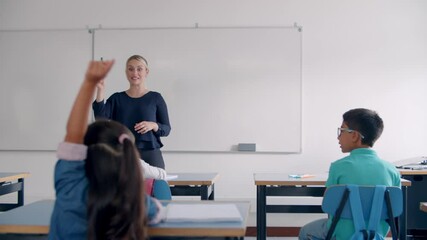 Primary school teacher interacting with pupils in class, asking questions and choosing for answer. Students raising hands at desks. Teaching or education concept