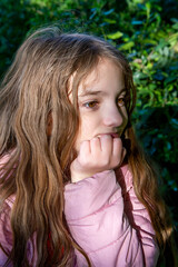 teen girl in pink jacket pretends to think on a sunny day